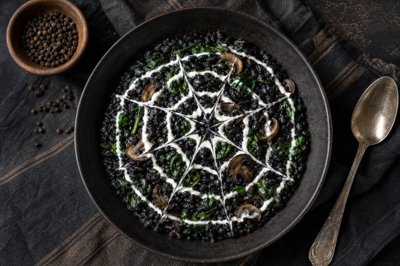 Black squid ink risotto with a cream spiderweb